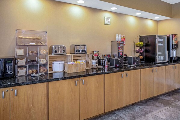 A breakfast area with a refrigerator, toaster, coffee maker, and various food items.