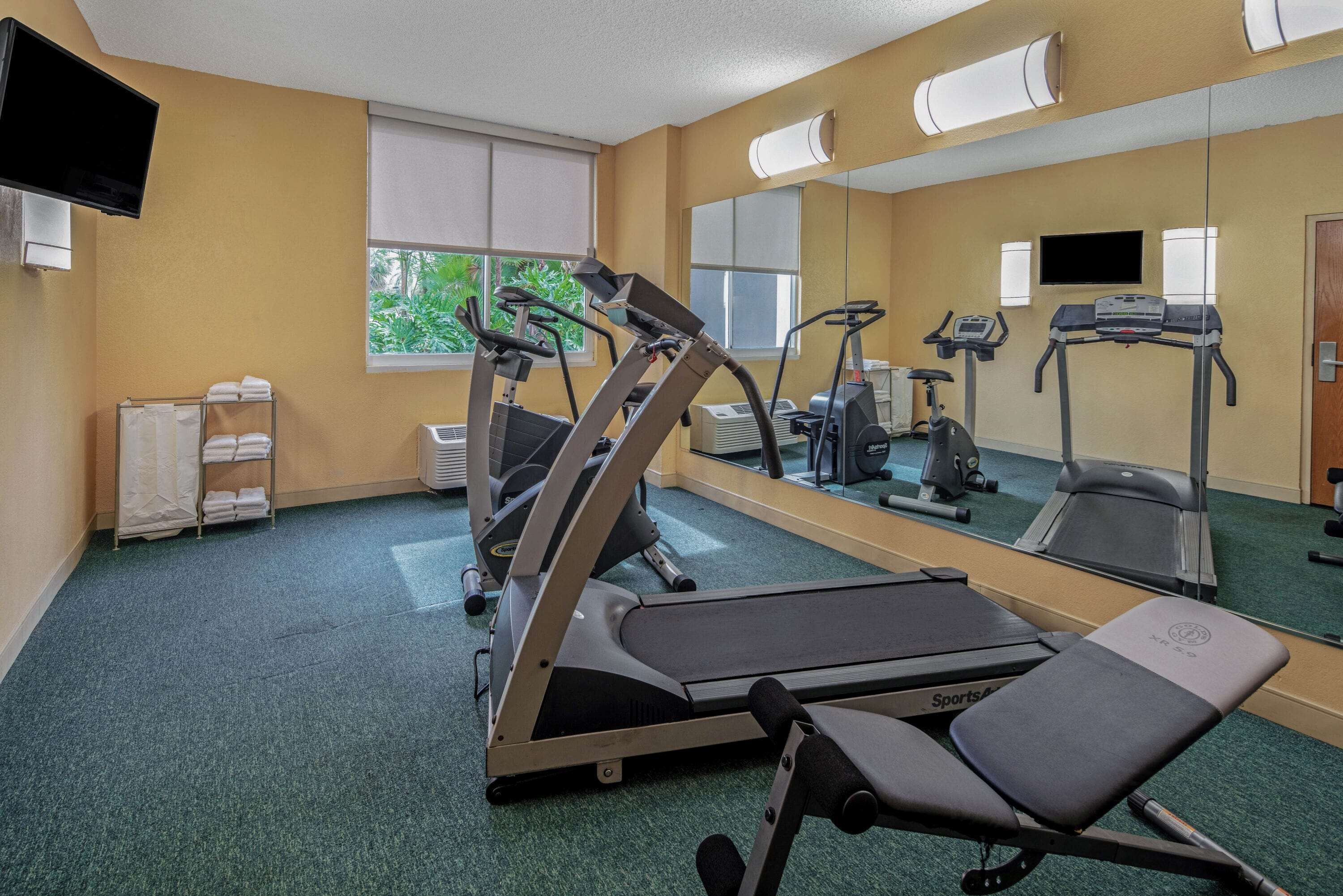 Une salle de sport équipée de matériel d’exercice, d’un miroir et d’un téléviseur.