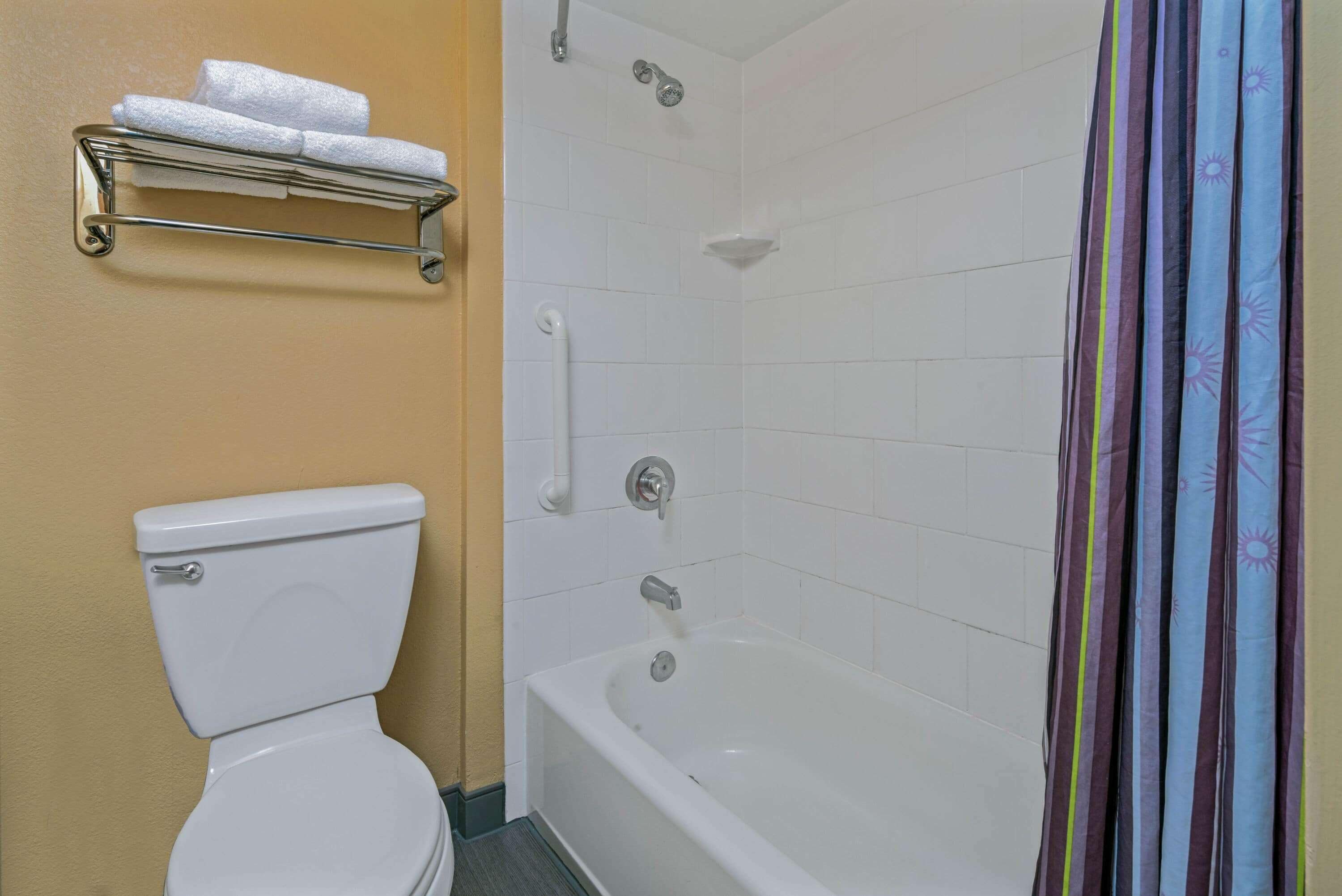 A bathroom with a toilet, a shower with a glass door, and a towel rack with two towels.
