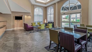 Un vestíbulo de hotel con zona de estar, mostrador de recepción y grandes ventanales.