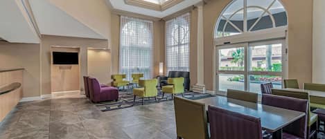 Un vestíbulo de hotel con zona de estar, mostrador de recepción y grandes ventanales.