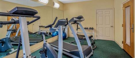 A gym with treadmills, elliptical machines, and free weights.
