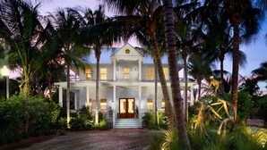 A large, two-story building with a symmetrical facade, a central entrance with a double door, and a balcony on the upper floor. - Parrot Key Hotel & Villas (Key West)