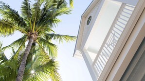 A tall palm tree with a white building in the background. - Parrot Key Hotel & Villas (Key West)