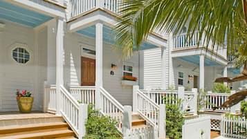 Una casa blanca con varios balcones, escalones de madera y una cerca blanca de piquetes.
