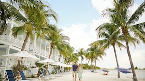 A beach with palm trees, lounge chairs, and umbrellas.