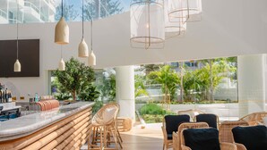 A modern bar area with a curved counter, wicker chairs, and hanging pendant lights. - The Brighton Hotel Sydney - MGallery Collection (Brighton-le-Sands)