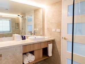 A modern bathroom with a large mirror, two sinks, a shower, and a towel rack. - The Brighton Hotel Sydney - MGallery Collection (Brighton-le-Sands)