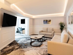 Una sala de estar moderna con un televisor de pantalla plana, un sofá, una mesa de centro y una alfombra estampada.