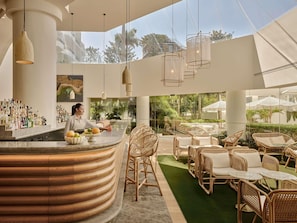 A bar area with a curved counter, wicker furniture, and a view of the outdoors.