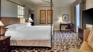Relax in comfort with a four-poster bed, desk, and sofa in this stylish hotel room.