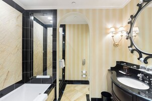 A modern bathroom with a large mirror, a bathtub, a sink, and a shower.