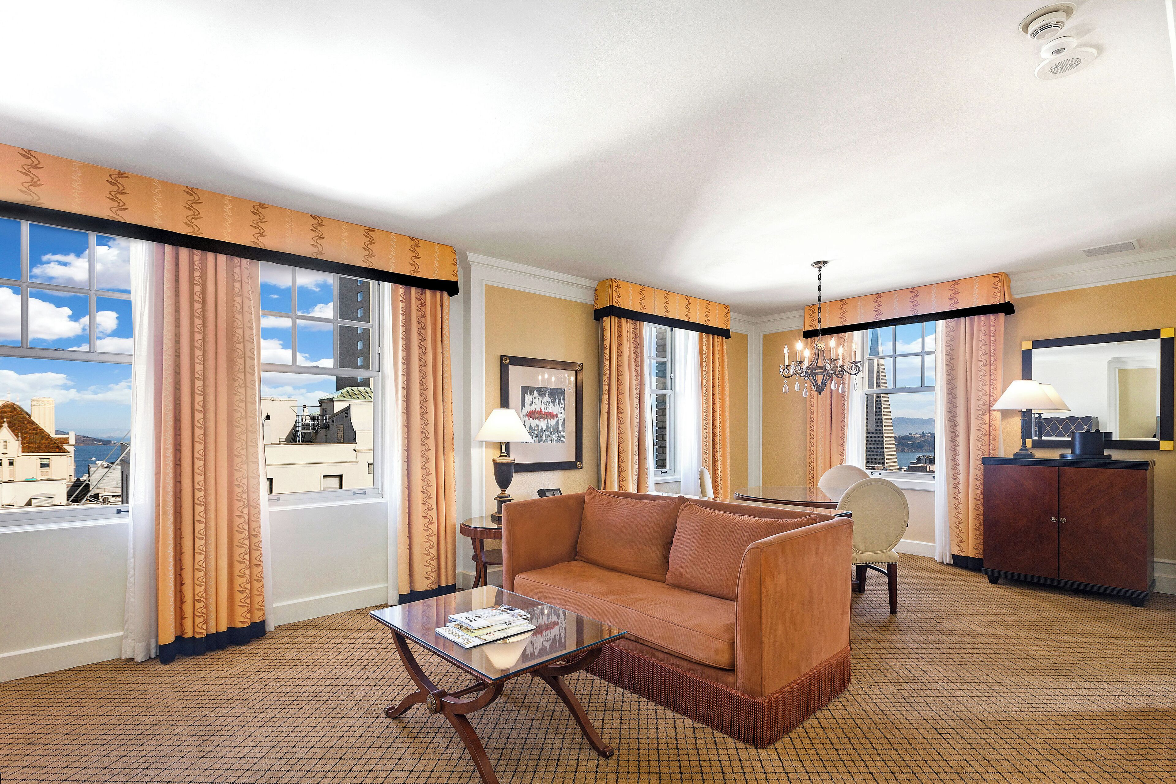 Une chambre d’hôtel avec un canapé, un fauteuil et une petite table avec une lampe.