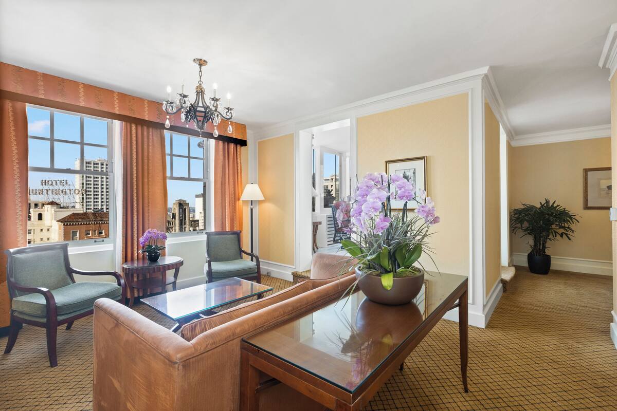 A hotel lobby with a seating area, a chandelier, and a large window with a view of the city.