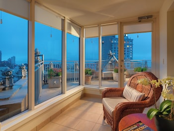 A balcony with wicker furniture, a potted plant, and a view of city buildings. at InterContinental Mark Hopkins by IHG