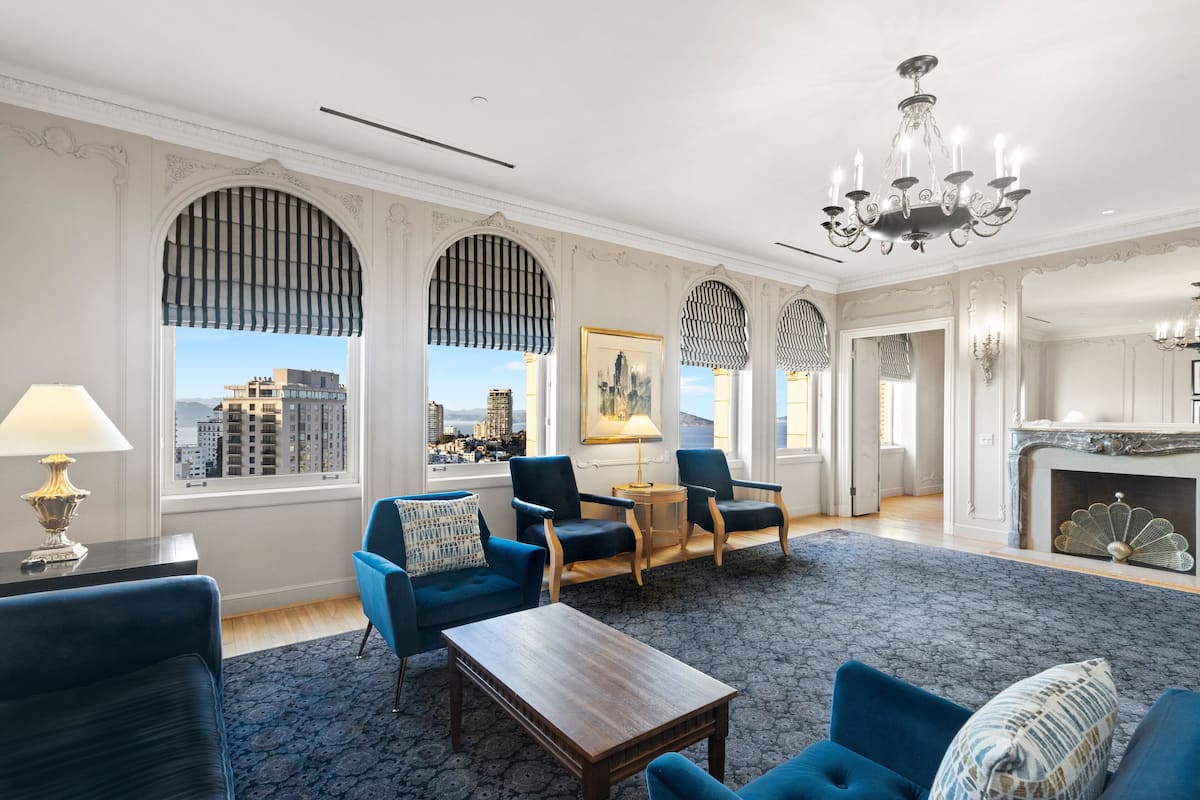 A spacious room with a large window, a chandelier, and a fireplace.