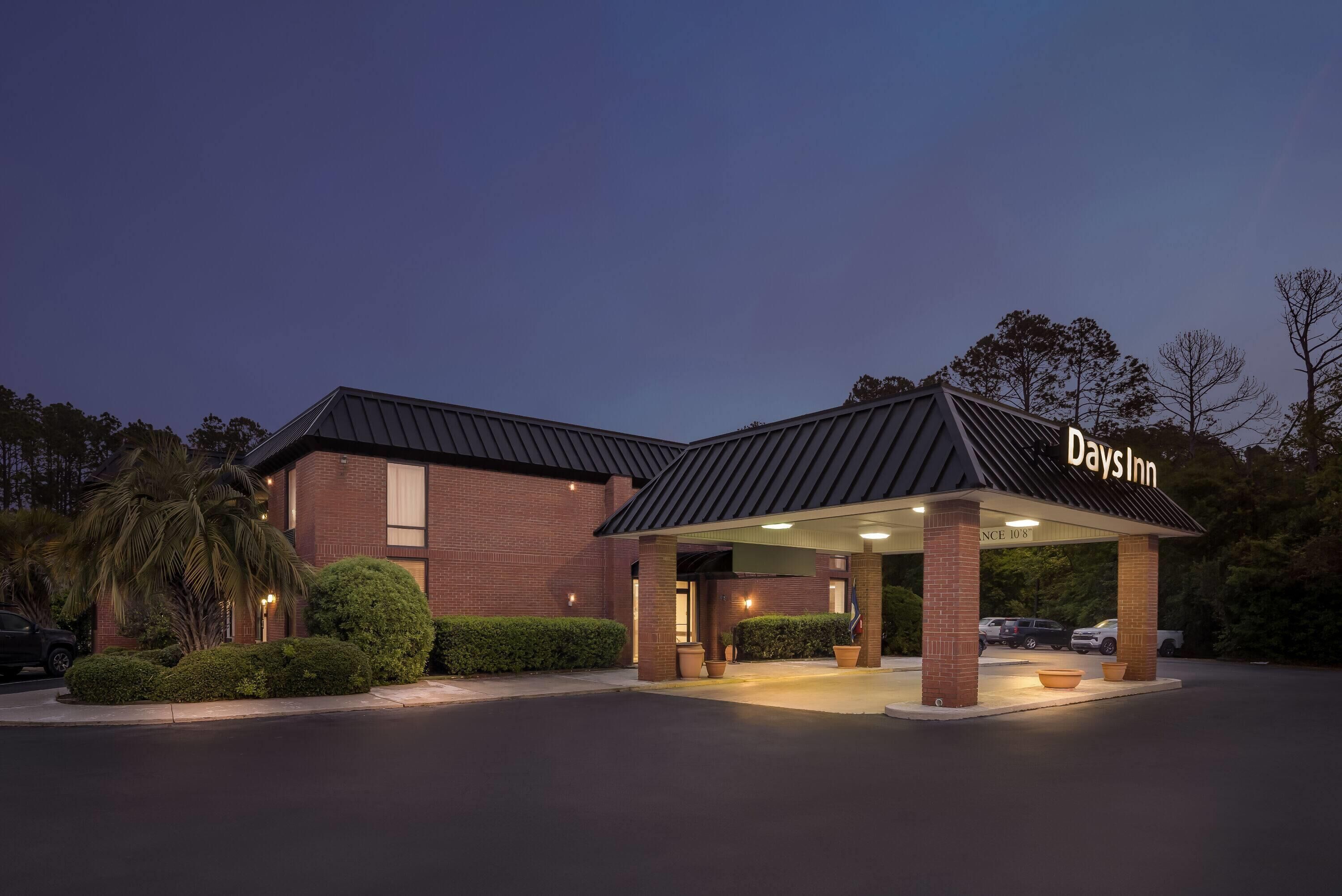 A Days Inn with a brick facade, covered parking area, and a well-lit entrance.