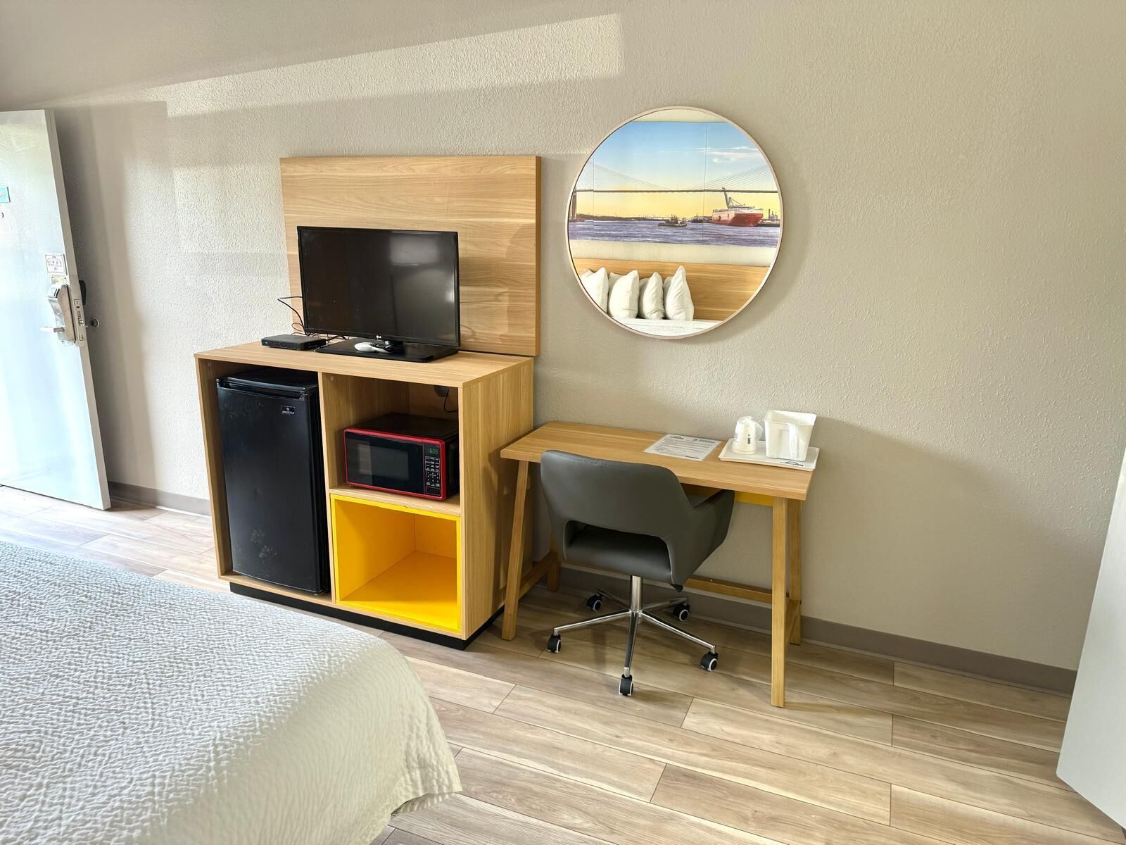 Una habitación de hotel con una cama, un escritorio con computadora, un microondas y un refrigerador.