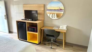 Una habitación de hotel con una cama, un escritorio con computadora, un microondas y un refrigerador.