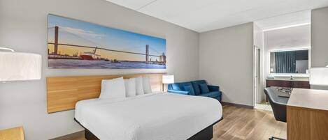 Habitación de hotel con una cama grande, un escritorio, una silla, un sofá y un cuadro de un puente.