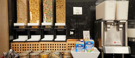 A breakfast bar with various food items, a coffee machine, and a sign indicating a 25% milk discount.
