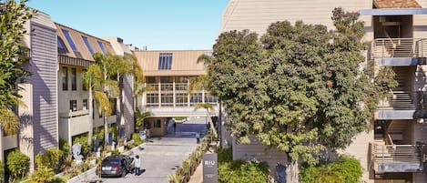 Un edificio moderno con techo plano, zona de estacionamiento y un letrero que dice "RIU".