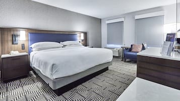 Una habitación de hotel moderna con una cama grande, un escritorio, una silla y una mesita.