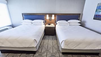 A hotel room with two beds, a patterned floor, and a wall-mounted light fixture.