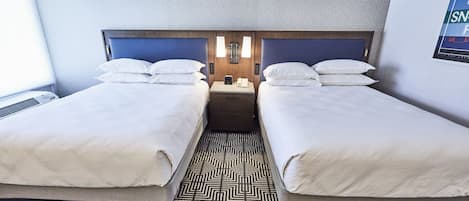 A hotel room with two beds, a patterned floor, and a wall-mounted light fixture.