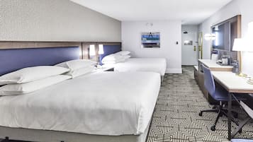 Habitación de hotel con dos camas, un escritorio, una silla, un espejo y un piso con diseño.