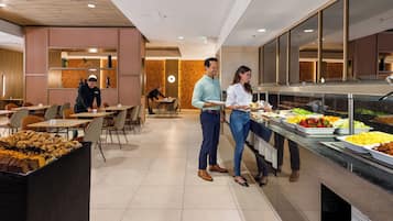 A buffet area with various food options, a seating area with tables and chairs, and a modern interior design.