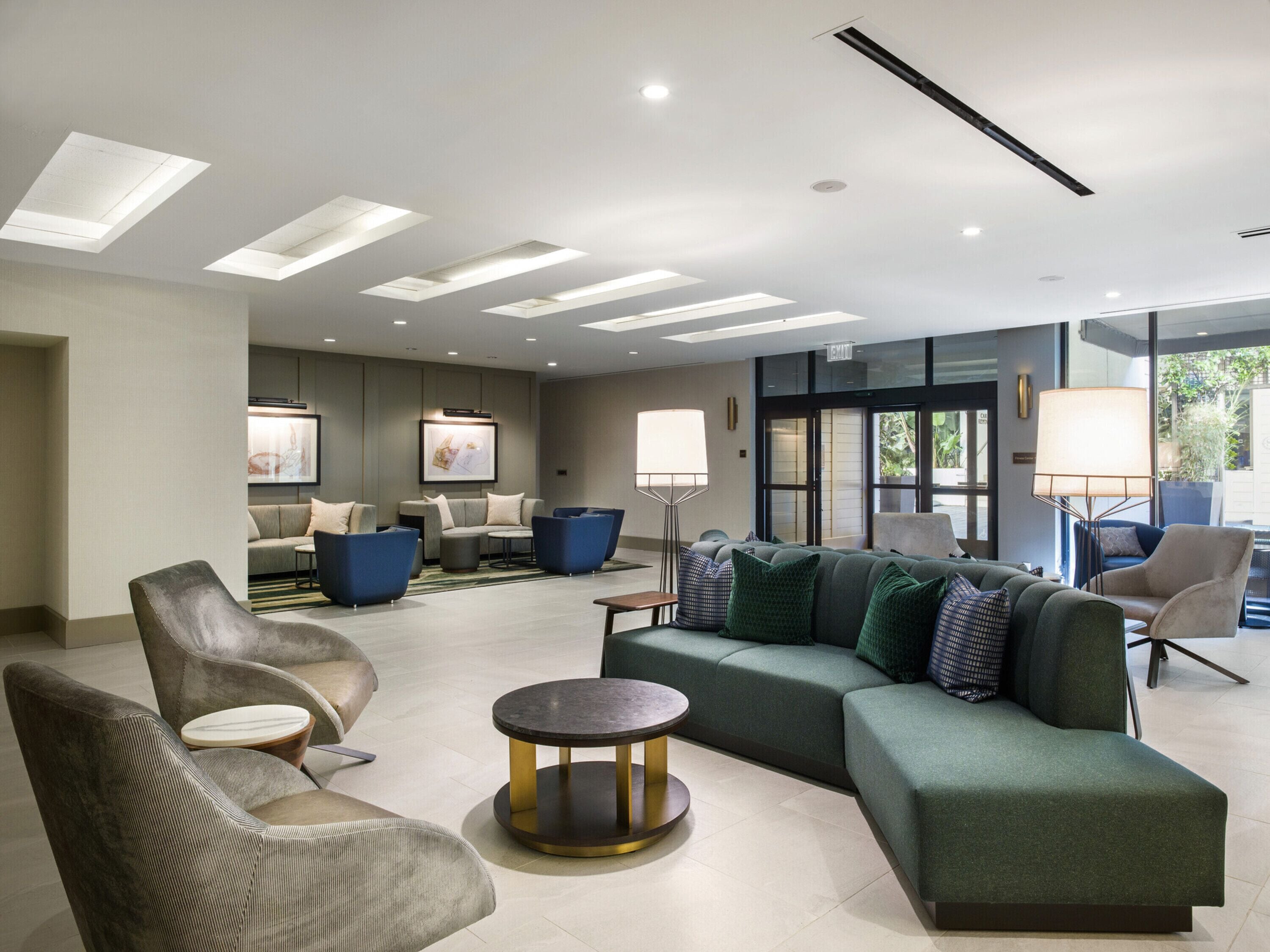 A modern lobby with a sectional sofa, armchairs, and a round table.