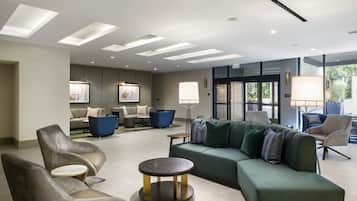 Um hall moderno com sofá de canto, poltronas e uma mesa redonda.