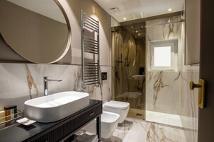 A modern bathroom with a large oval sink, a glass shower enclosure, and a marble-tiled floor.