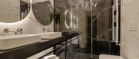 Une salle de bain moderne avec un grand miroir, deux lavabos, une douche et des toilettes.