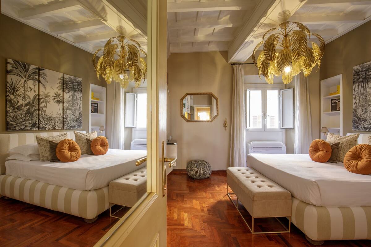 A room with two beds, a mirror, and a ceiling fan.