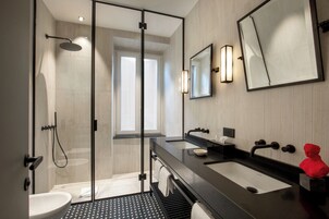 Un bagno moderno con doccia vetrata, uno specchio grande e un piano lavabo nero con lavandino.