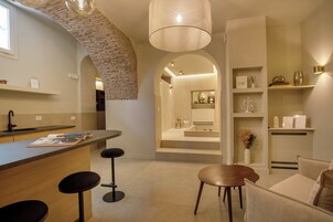 A modern kitchen with a brick arch, a bar area with stools, and a seating area with a round table.