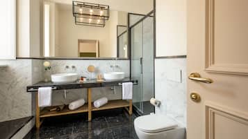Un baño moderno con dos lavamanos, cabina de ducha de cristal y un inodoro.