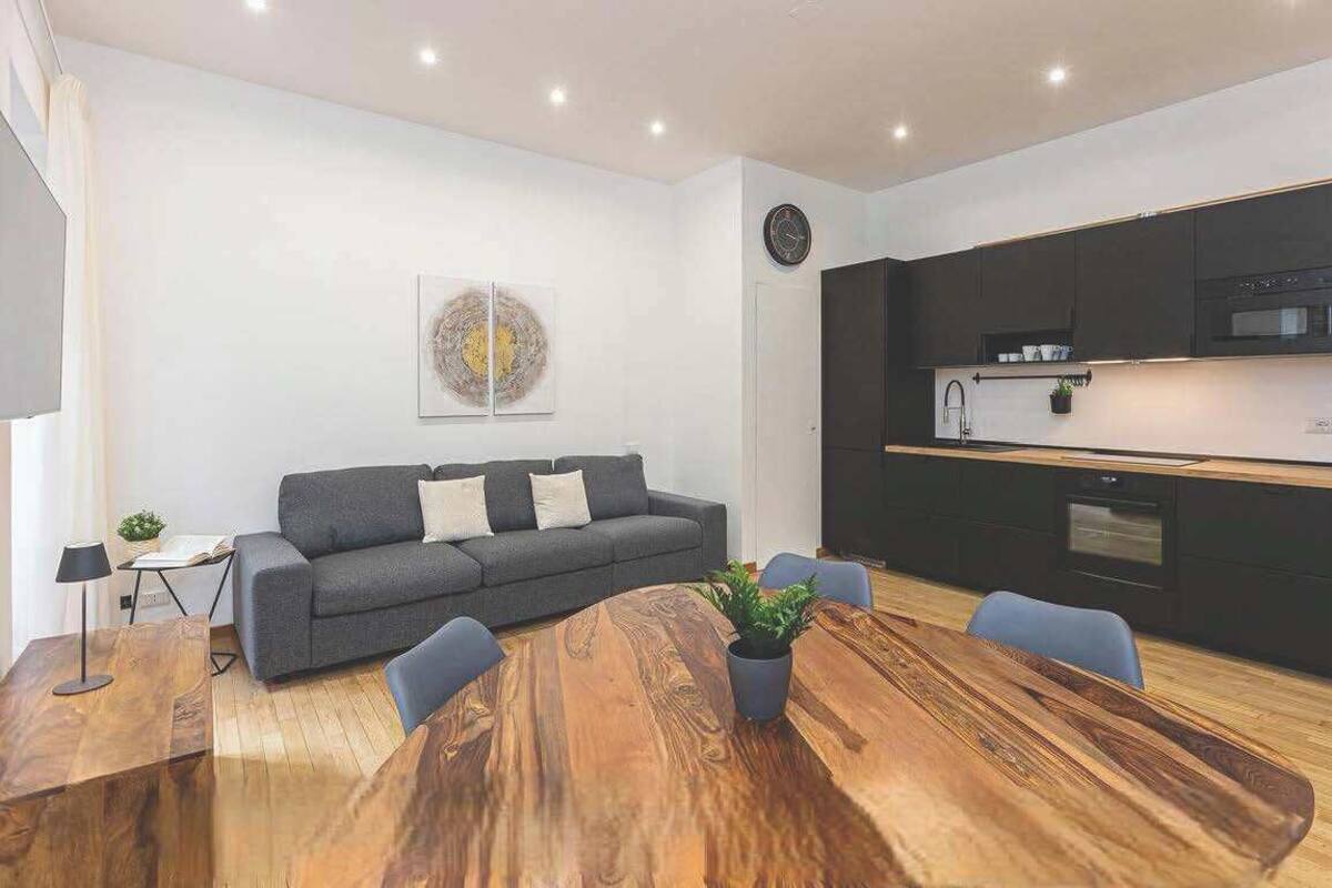 A modern living space with a sofa, dining table, and kitchen area.