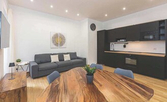A modern living space with a sofa, dining table, and kitchen area.