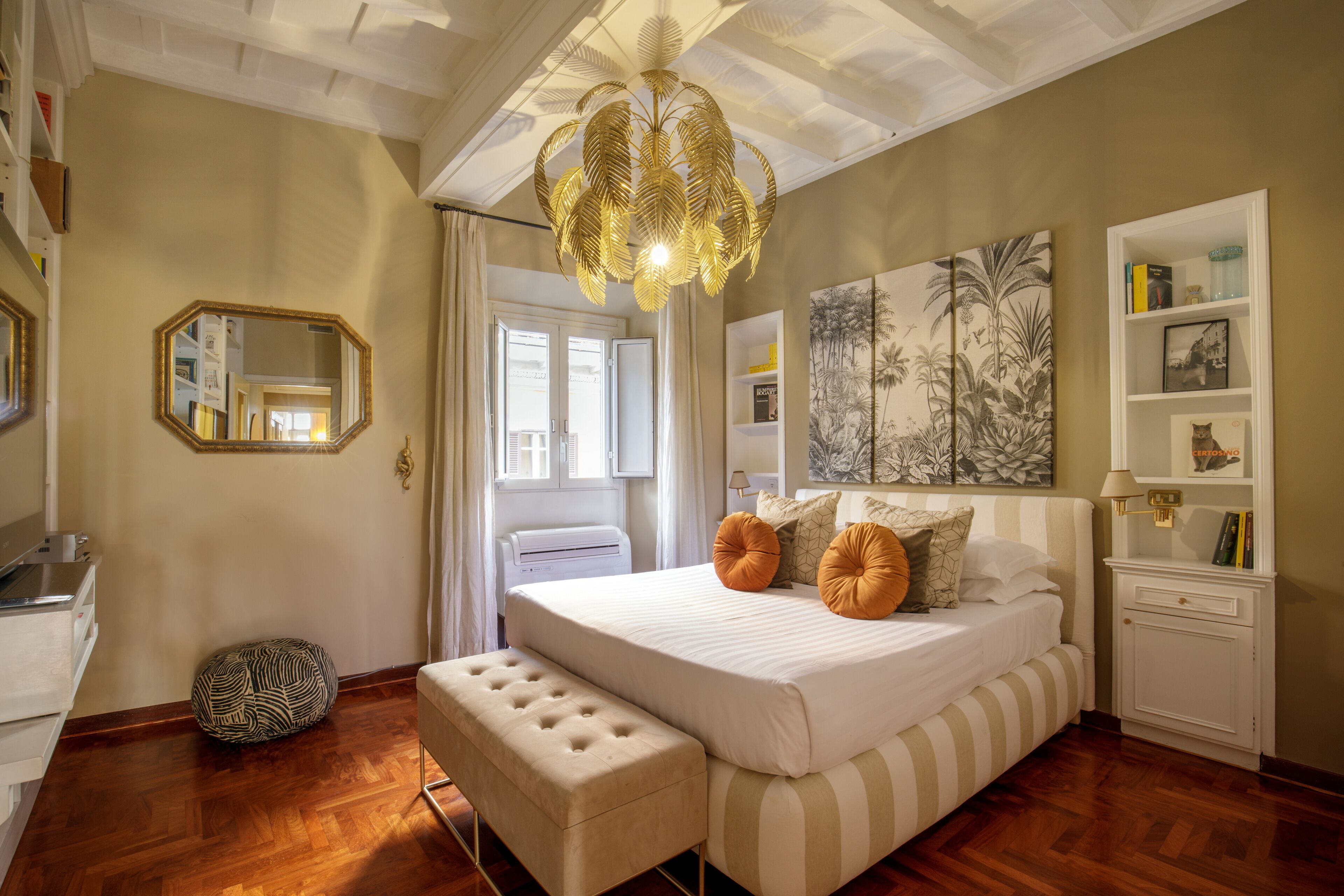 A bedroom with a large bed, a bedside table, a mirror, and a ceiling fan.