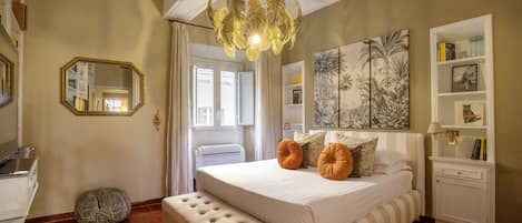 A bedroom with a large bed, a bedside table, a mirror, and a ceiling fan.