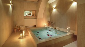 Une salle de spa moderne avec une grande baignoire, des bougies et des fleurs.