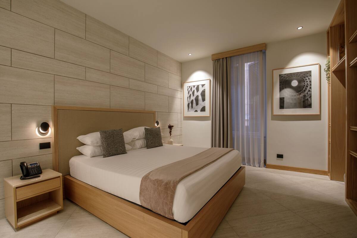 A modern hotel room with a large bed, bedside tables, and artwork on the walls.