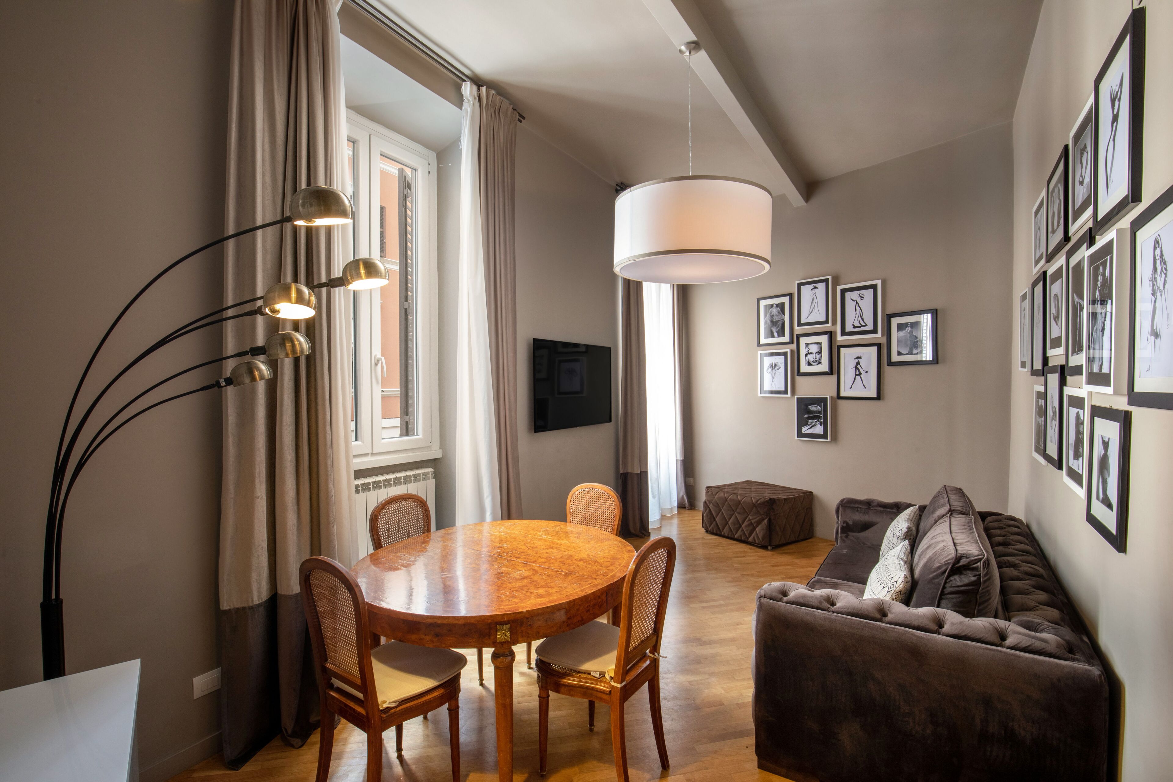 A dining area with a round table and chairs, a sofa, and a hanging light fixture.
