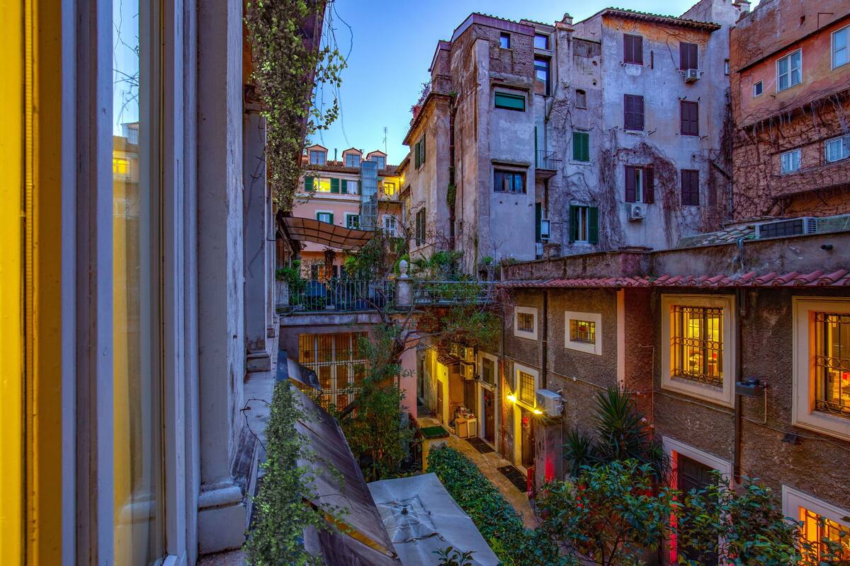 A narrow alleyway with buildings on either side, featuring balconies and windows.