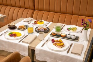 A breakfast setting with a variety of dishes, including eggs, toast, and fruit, on a table with a white tablecloth.