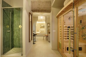 A hotel hallway with a glass shower, a wooden sauna area, and a central seating area with a table and chairs. -  Condotti Boutique Hotel (Rome)