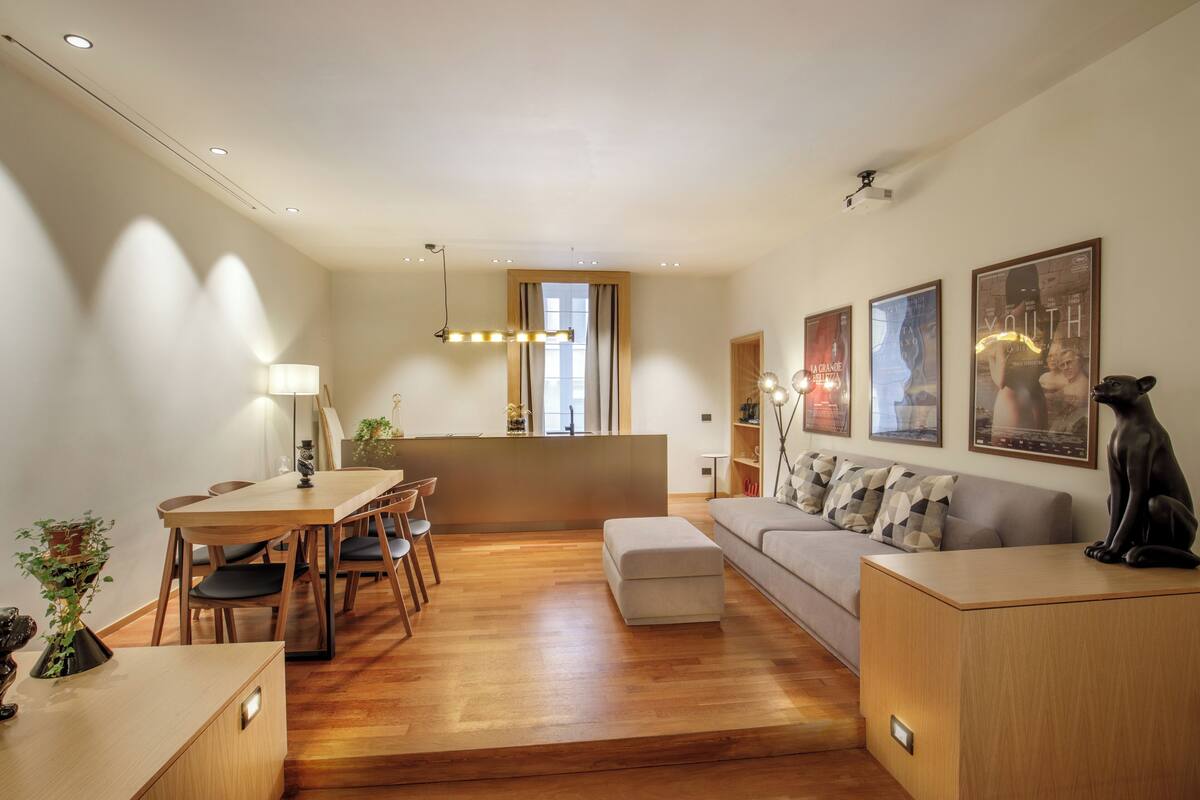A modern living room with a wooden dining table, sofa, and a decorative statue.